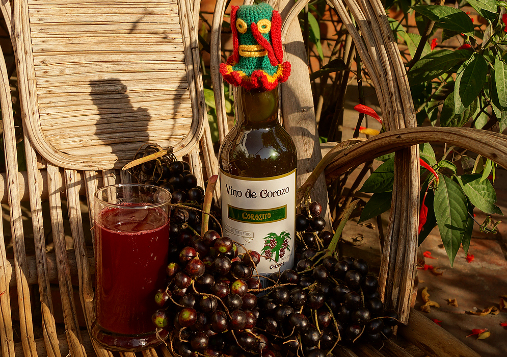 A bottle of corozo wine, a glass of corozo juice and corozo berries