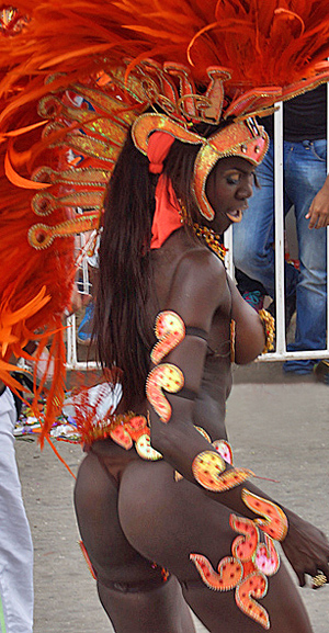 Dark-skinned carnival dancer in a striking orange feathered costume performing during the Barranquilla Carnival parade