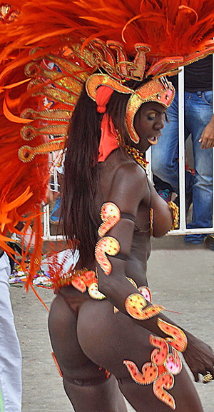 Dark-skinned carnival dancer in a striking orange feathered costume performing during the Barranquilla Carnival parade