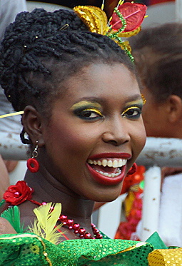 Joyful Barranquilla Carnival Performer Smiling Afro-Colombian woman in a vibrant green costume with glitter, red flowers, and golden eye makeup, radiating happiness during the Barranquilla Carnival