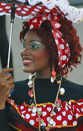 Carnival Performer in Polka Dot Costume with Umbrella Smiling Afro-Colombian woman wearing a red and white polka dot outfit with matching headscarf and necklace, holding a festive umbrella during the Barranquilla Carnival