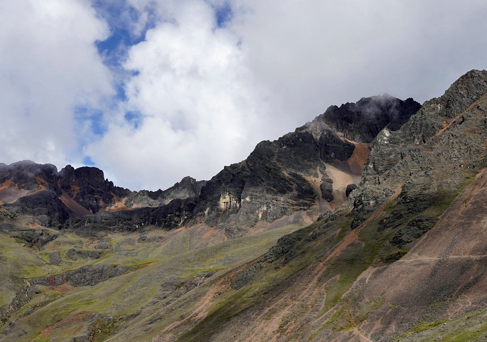 Cordillera Vilcanota Orange Peaks Dramatic cliffs and slopes of the Vilcanota range painted with streaks of orange and black volcanic rock under high-altitude clouds