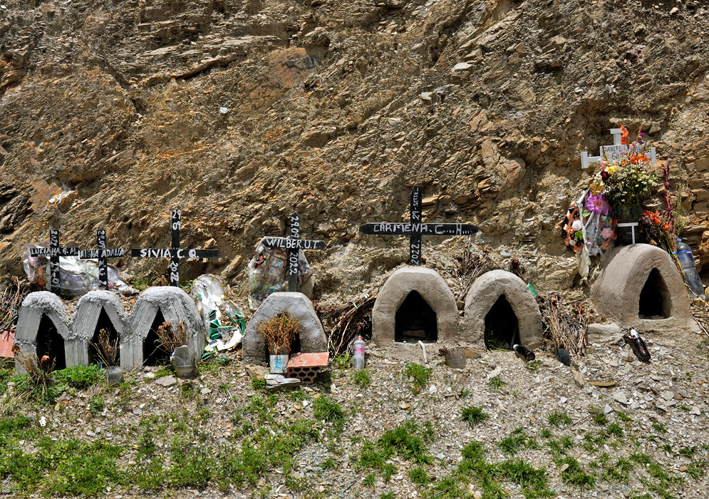 Animitas Roadside Shrines Peru Small roadside shrines known as animitas, each marked with crosses and miniature domed structures, placed against a rocky hillside in memory of individuals who died in accidents along this mountain road