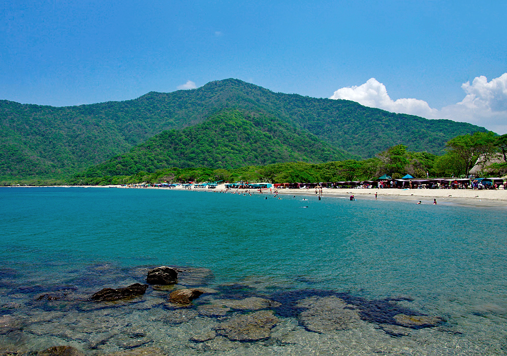 Bahia Concha beach during the wet season with white sand and green mountains