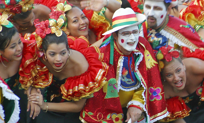 Energetic dance troupe in traditional red and black costumes and white face paint celebrating during Barranquilla Carnival