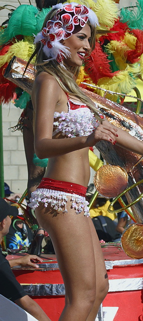 Smiling blonde woman in a festive red and white bikini costume dancing on a float at the Barranquilla Carnival parade
