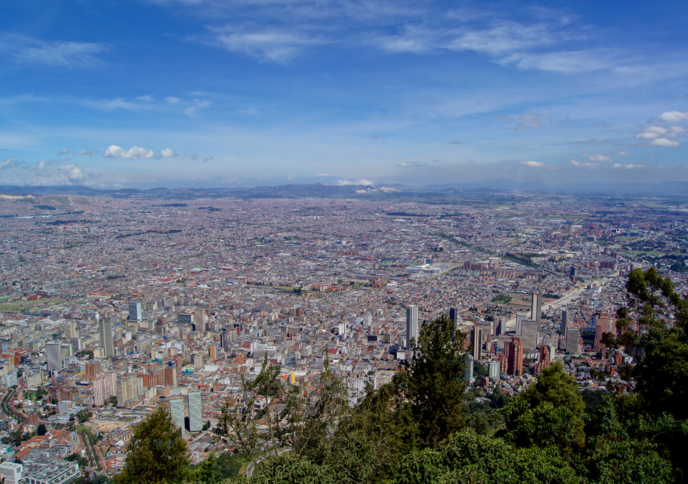 A vista of Bogotá under dark blue skies with a snow-cap mountain in the central Andes in the background