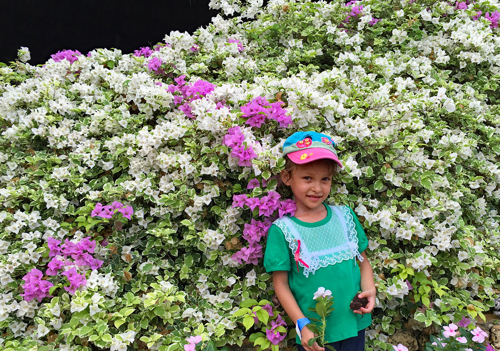 Pretty girl standing in front of a bougainvillea bush with white and pink bracts