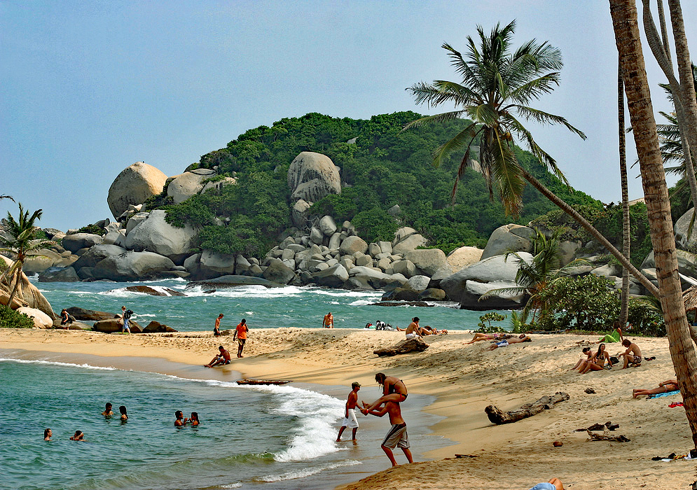 Rocks, blue water, beach and sunbathers