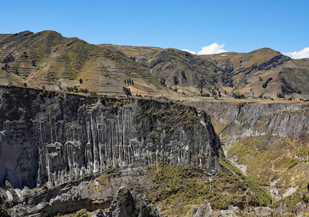 Toachi River Canyon Rock Formations Dramatic vertical rock formations line the cliffs of the Toachi River Canyon with patchworked farmland and Andean mountains in the background