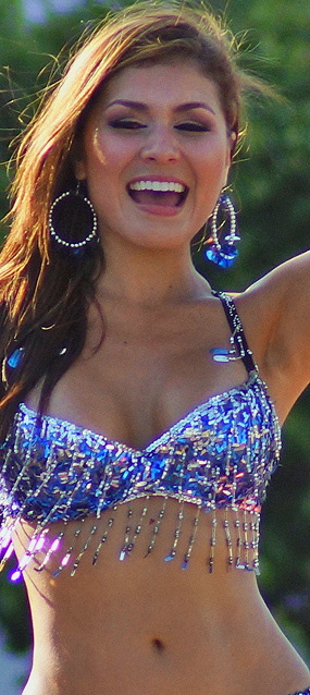Smiling young woman in a sparkling blue sequin costume dancing joyfully during the Barranquilla Carnival parade