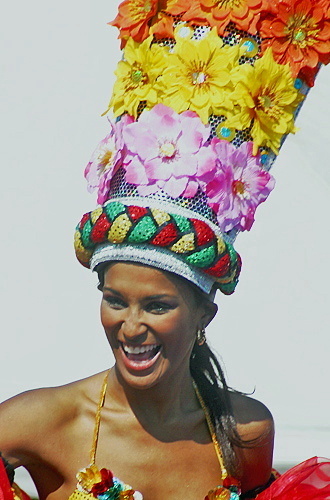 Joyful Barranquilla Carnival dancer in a colorful floral headdress and vibrant costume, smiling radiantly during the parade