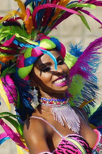 Joyful Colombian carnival dancer in a colorful feathered headdress and sparkling costume smiling radiantly during the parade