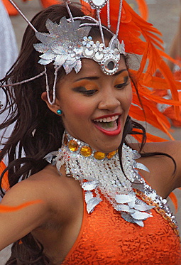 Carnival Dancer in Orange and Silver Joyful Barranquilla Carnival performer in an orange outfit with shimmering silver accessories and a decorative feathered headdress, dancing with a wide smile