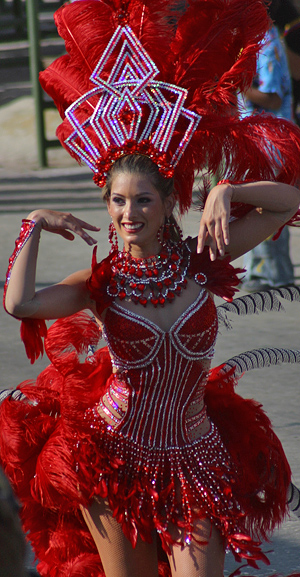 Carnival dancer in an elaborate red feathered costume and headdress performing during a Barranquilla parade