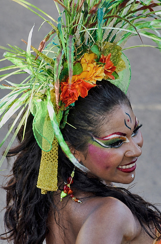 Smiling Barranquilla Carnival dancer in tropical flower headdress and bold face paint looking over her shoulder