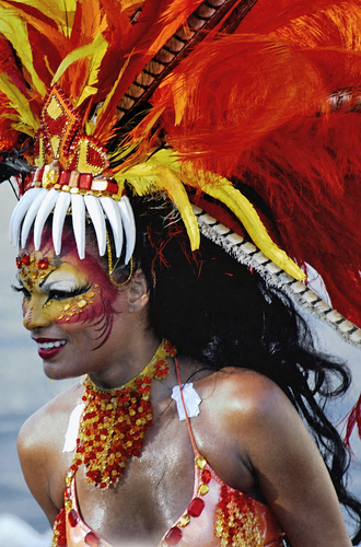Barranquilla Carnival performer in red and yellow costume with dramatic face paint and jaguar tooth headdress parading at night