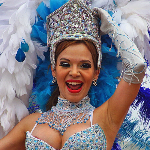 Colombian carnival queen in sparkling blue and white costume with feathered headdress smiling during Barranquilla Carnival