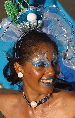 Carnival Dancer with Blue Sea-Themed Makeup Smiling Colombian woman wearing bold blue face paint and lipstick, a decorative blue and white headpiece, and glittery eye designs during the Barranquilla Carnival