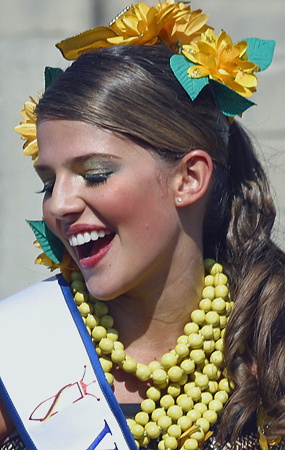 Barranquilla Carnival Queen with Yellow Flowers Smiling young woman wearing a sash, bold yellow necklace, and yellow flower hair accessories, enjoying the festivities during the Barranquilla Carnival parade