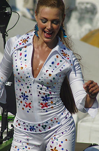 Smiling Colombian woman in a fitted white carnival outfit decorated with colorful gemstones, dancing during the parade
