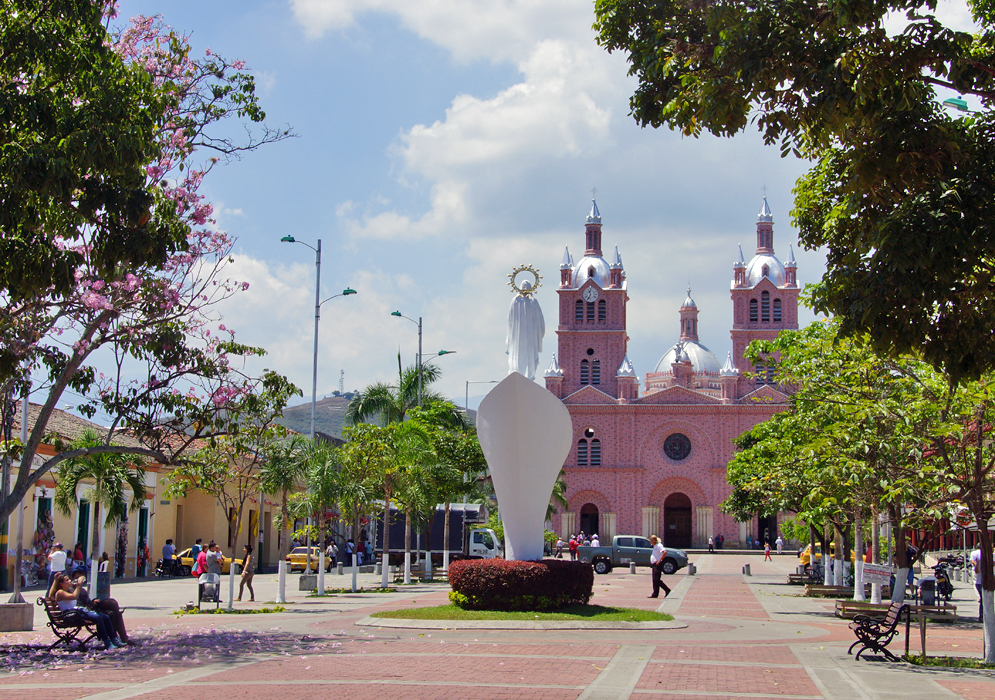 Pink cathedral with white a statue of Jesus in front of the church