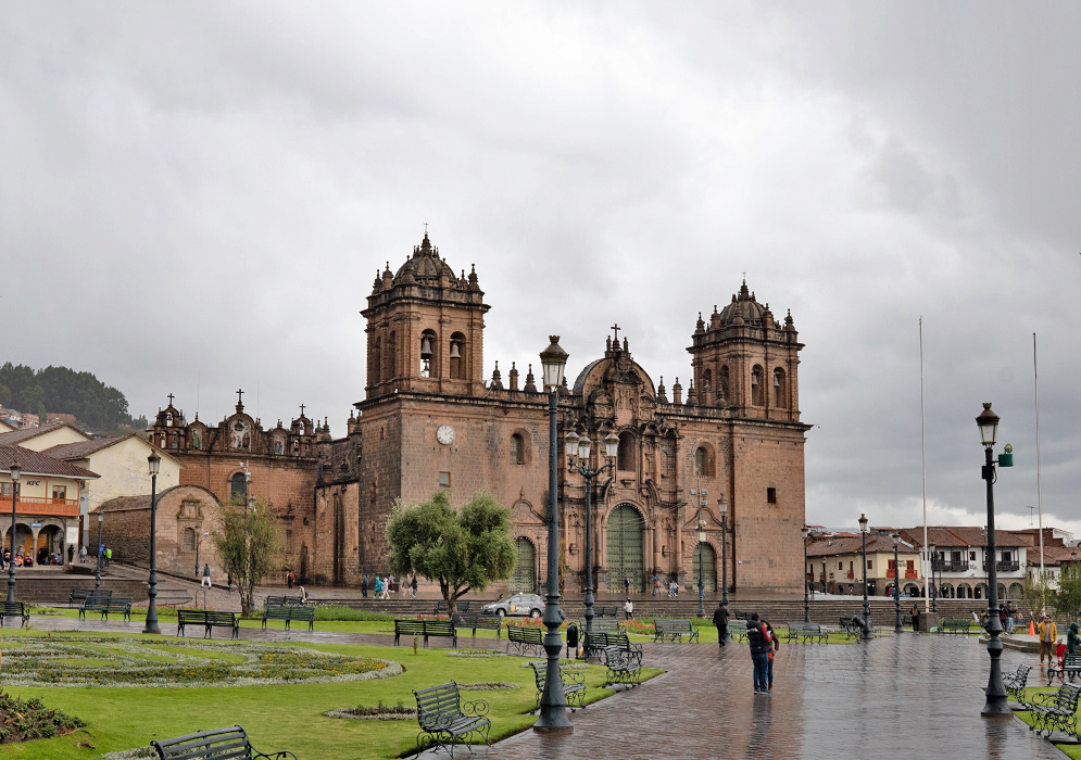 Cusco Cathedral Basilica Peru The Cathedral Basilica of the Assumption in Cusco on a cloudy day, viewed from the plaza with wet cobblestones and green garden paths