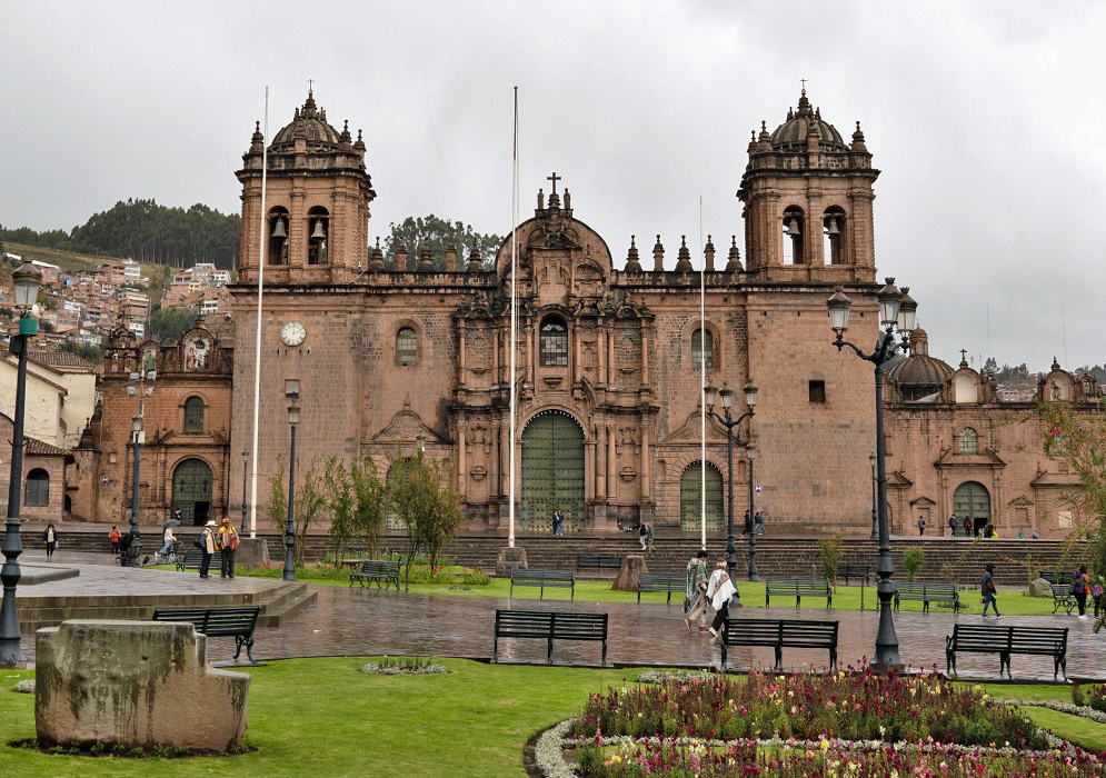 Cusco Cathedral on a Rainy Day Front view of Cusco Cathedral under gray skies, with surrounding greenery and people in raincoats