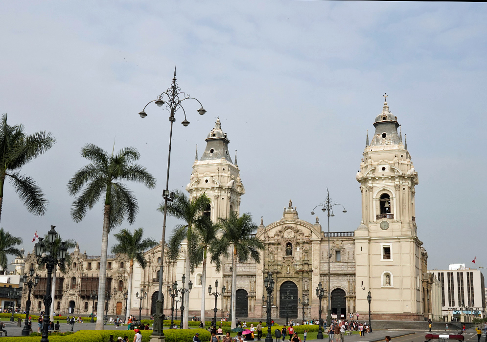 Cathedral of Lima Wide-angle image of the Cathedral of Lima and surrounding historic buildings, framed by palm trees and people enjoying the green plaza