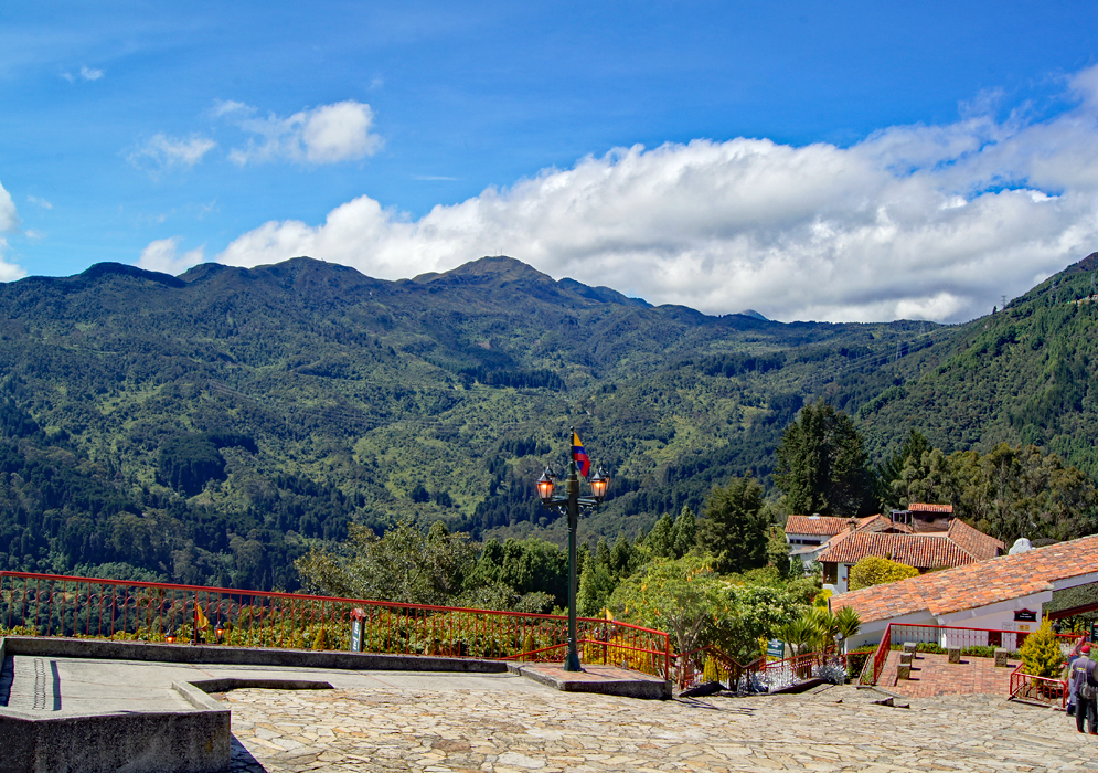 Red-tile roof houses on the top of Cerro de Monserrate with the green Andes in the background under blue skies