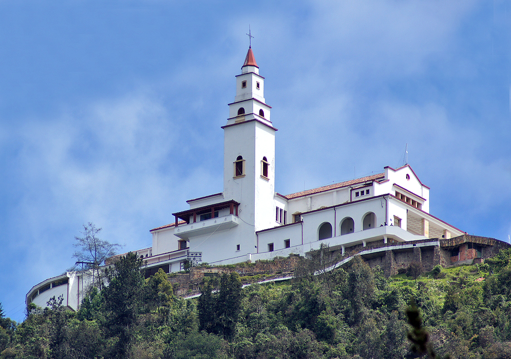 The white Monserrate Monastery at the edge of a hill under blue skies
