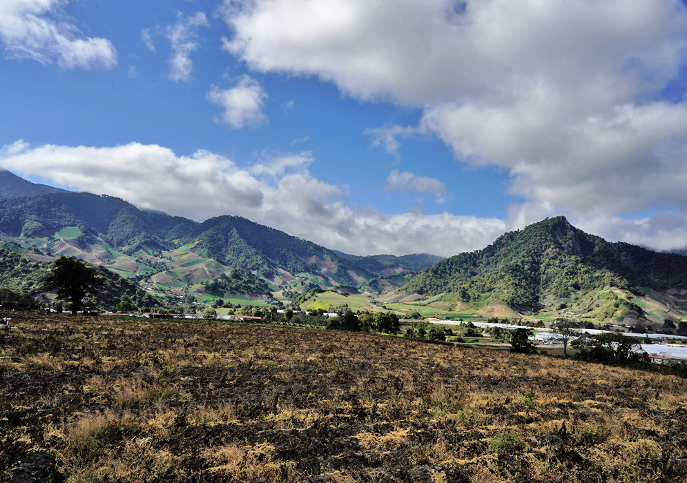 Cerro Punta Agricultural Slopes Tidy patchwork fields and sloping green ridges define the fertile Cerro Punta valley in western Panama, set beneath dramatic cloud shadows and blue skies
