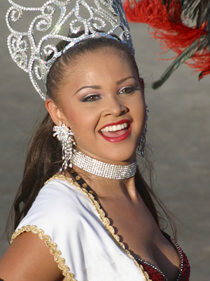 Smiling Colombian carnival queen in silver tiara and white outfit during the parade