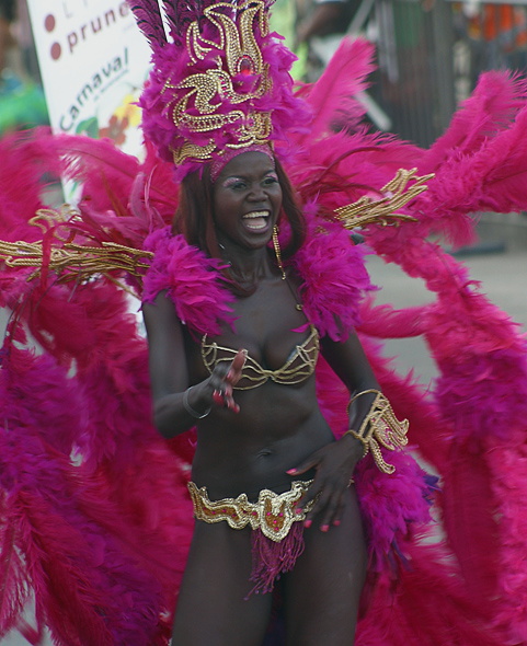 Vibrant Barranquilla Carnival Performe Joyful Afro-Colombian woman in a dazzling magenta and gold feathered costume, smiling and dancing during the Barranquilla Carnival parade