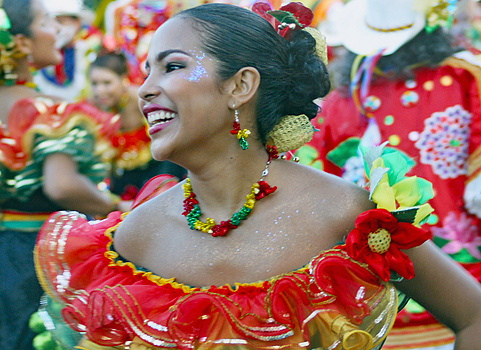Colombian Carnival Joy Smiling Colombian woman in a colorful red, green, and yellow traditional costume with glitter on her cheek, dancing during the Barranquilla Carnival celebration