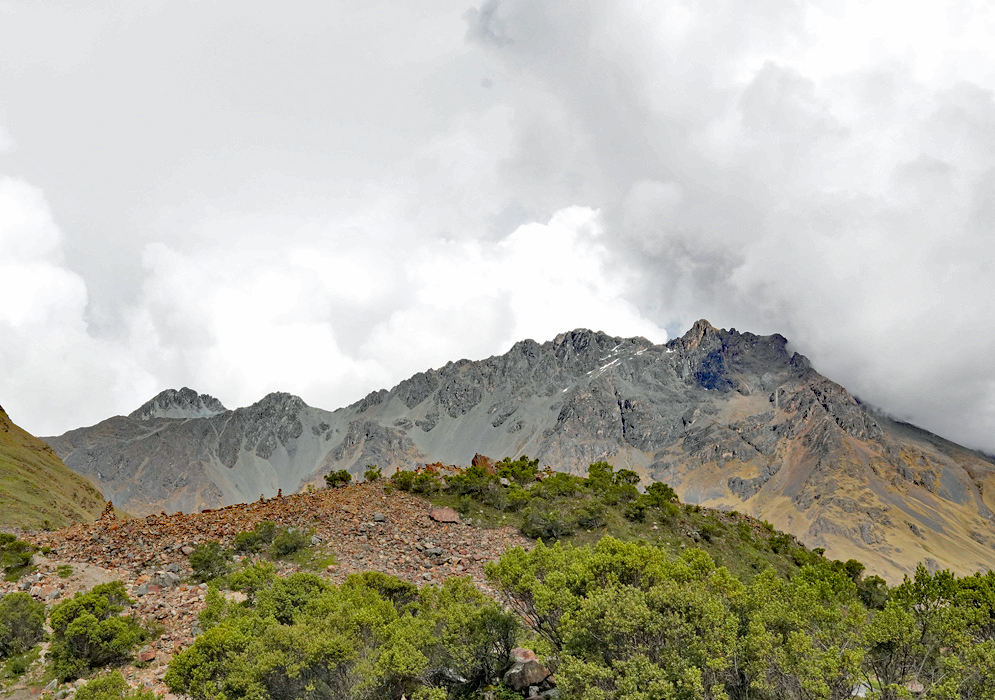 Cordillera De Vilcabamba Peaks A dramatic ridgeline of jagged peaks in the Cordillera de Vilcabamba near Humantay, with rocky terrain and scattered green shrubs beneath a cloudy Andean sky