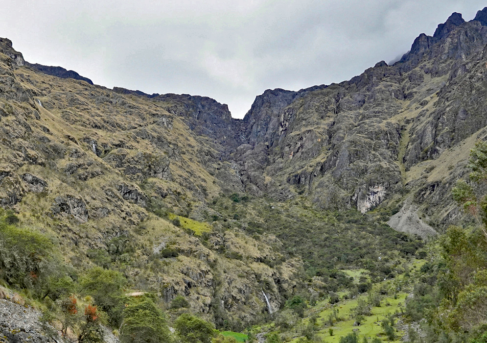 Cordillera Vilcabamba Canyon Steep, rugged cliffs of the Cordillera Vilcabamba form a narrow canyon with sparse vegetation and pockets of bright green forest at the bottom