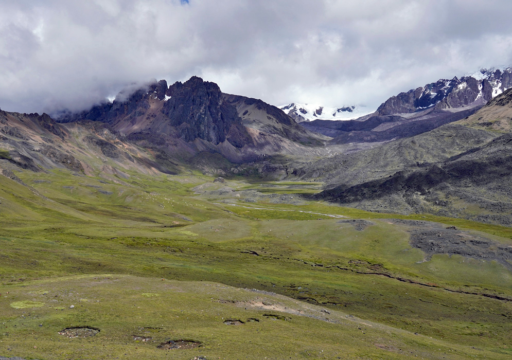 Cordillera Vilcanota Valley Peru Panoramic view of a high-altitude green valley surrounded by dark rocky peaks and snow-capped ridgelines in Peru’s Cordillera Vilcanota