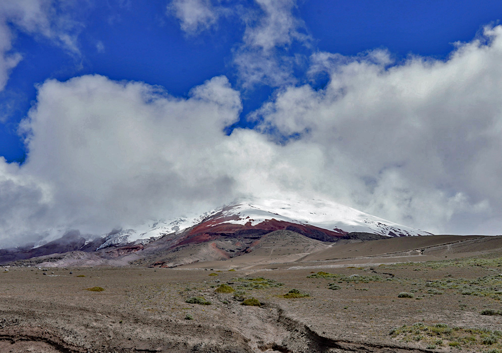 Cotopaxi’s Snowy Crater Ridge A close-up view of Cotopaxi’s white summit emerging from thick clouds above dark rocky slopes