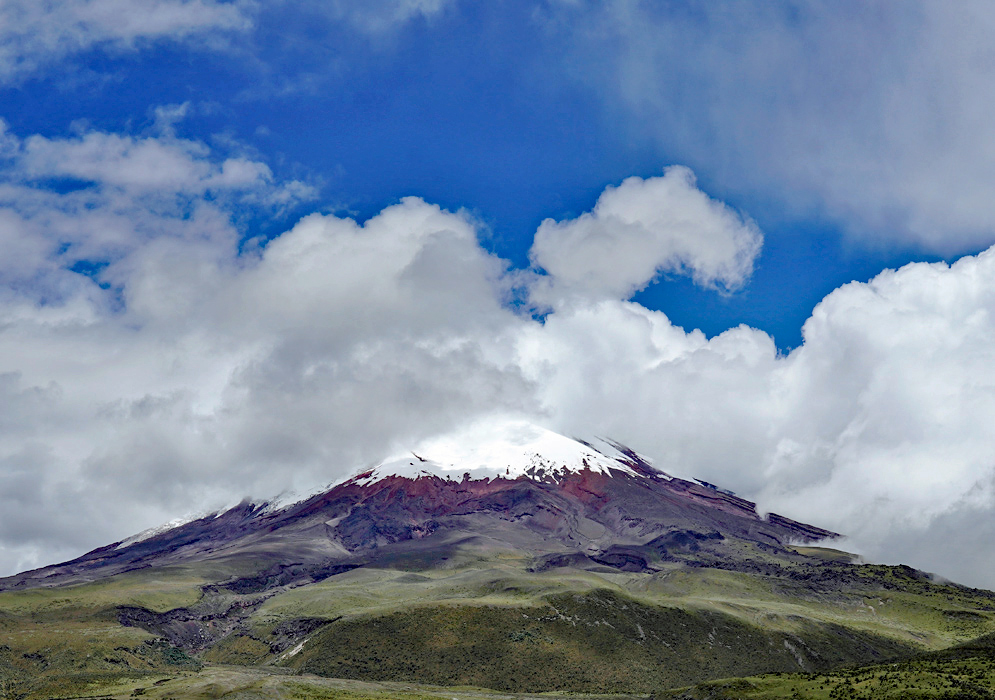 Snow-Capped Cotopaxi Volcano Snow-covered Cotopaxi volcano rises above a dry, rocky foreground under a thick blanket of clouds