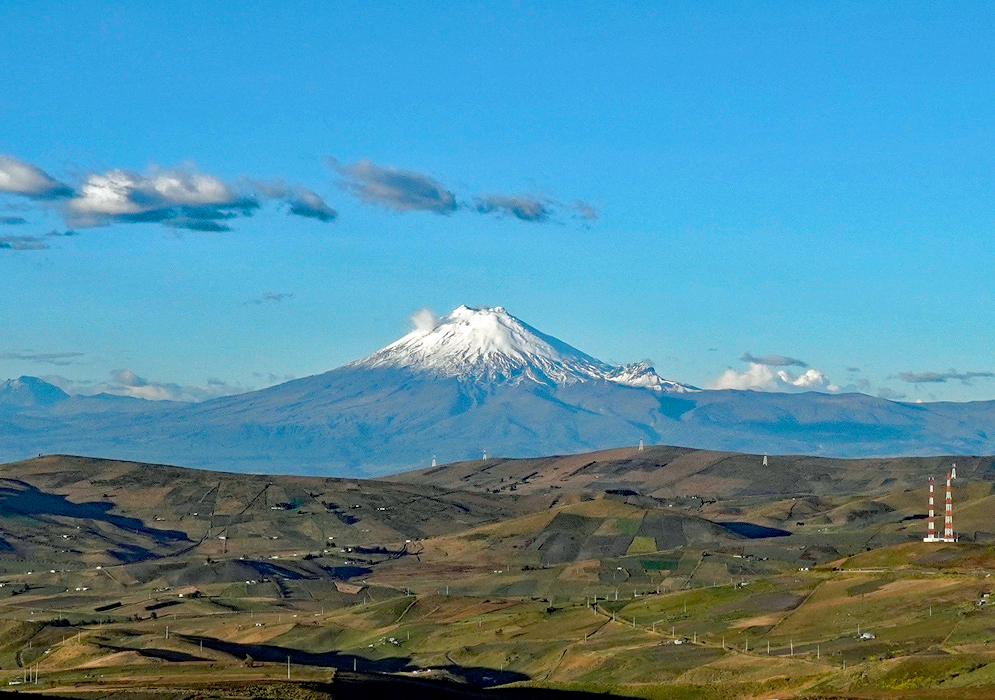 Cotopaxi Volcano Landscape The iconic conical shape of Cotopaxi Volcano dominates the landscape with its snow-covered summit framed by open farmland and a clear blue sky