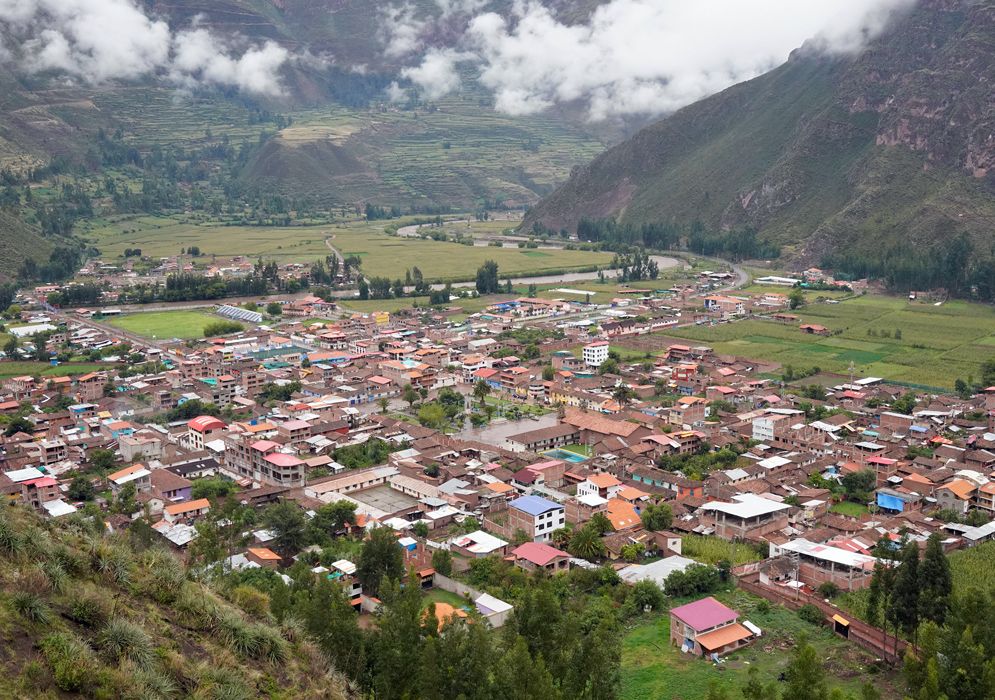 Town of Coya in Sacred Valley Aerial view of the rural town of Coya nestled in Peru's Sacred Valley, surrounded by steep green mountains, farmland, and scattered clouds.