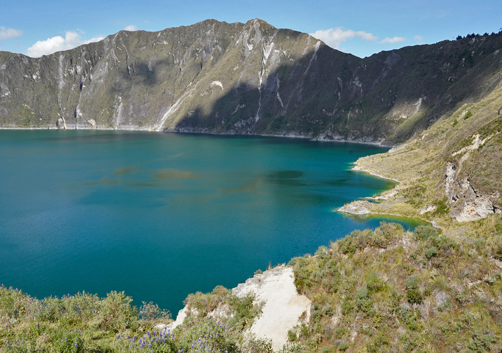 Quilotoa Lake Basin The deep waters of Quilotoa Lake filling a steep volcanic basin, viewed from a high trail lined with shrubs