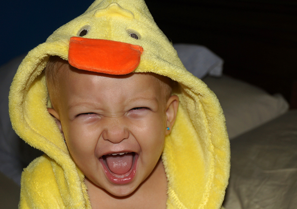 A vrey haapy baby girl with a yellow duck outfil
