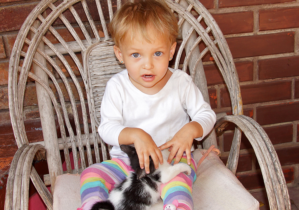 One-year-old girl with blonde hair and blue eyes with her cat