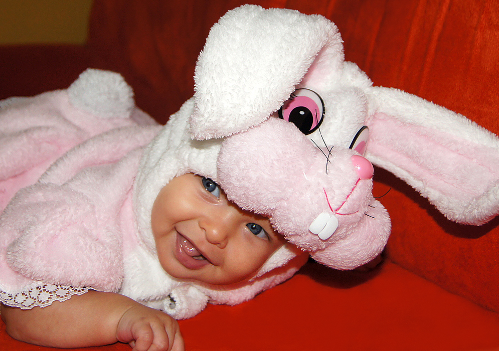 A happy baby girl with a pink rabbit outfit