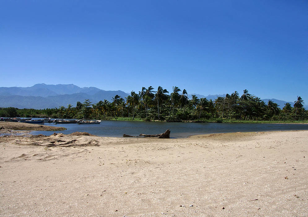 River flowing short of the sea, with beach on the foreground and mountains in the background