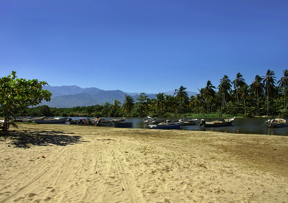 River, boats and Santa Marta mountains in the background at Dibulla Beach