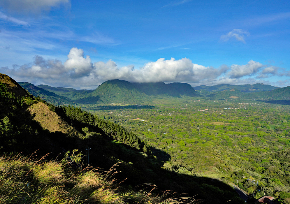 El Valle de Antón Panama Wide-angle view of El Valle de Antón in Panama showing a vast forested valley surrounded by steep volcanic mountains under a partly cloudy sky