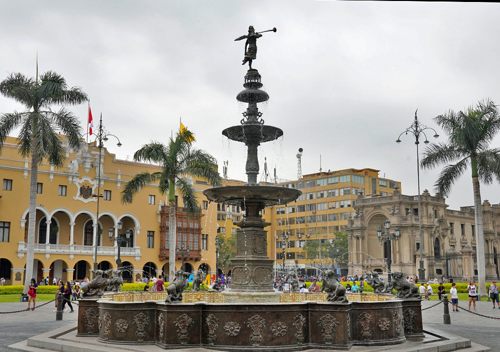 Fuente de la Plaza Mayor Close-up of the ornate bronze fountain in the center of Plaza Mayor de Lima, surrounded by palm trees and colonial-era buildings